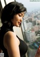 A woman in a black dress looking out a window.