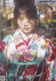 A woman in a colorful kimono poses for a picture.