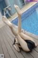 A woman laying on a wooden deck next to a swimming pool.