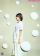 A woman standing in front of a wall of white circles.