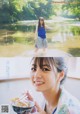 A woman holding a bowl of food in front of a lake.