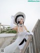 A woman in a white dress and hat posing for a picture.