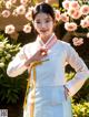 A young girl wearing a white hanbok standing in front of flowers.