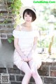 A woman sitting on a brick wall wearing a hat.