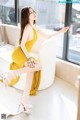 A woman in a yellow dress sitting on a white couch.