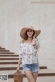 A woman wearing a straw hat and a white top.