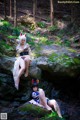 A couple of women sitting on top of a rock in the woods.